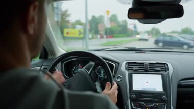 Yağmurlu bir günde araba süren adam yola odaklanıyor. Sürücü erkek, trafiğe bakıyor ve direksiyonu çeviriyor. Güvenli sürüş