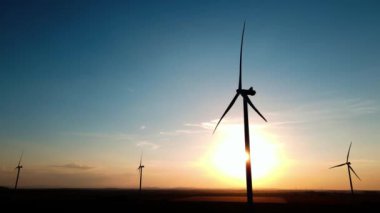 Gün batımında kırsal alanda siluetli rüzgar türbinleri. Rüzgar santrali temiz enerji üretiyor. Yenilenebilir ve sürdürülebilir enerji kavramı