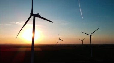 Gün batımında kırsal alanda siluetli rüzgar türbinleri. Rüzgar santrali temiz enerji üretiyor. Yenilenebilir ve sürdürülebilir enerji kavramı