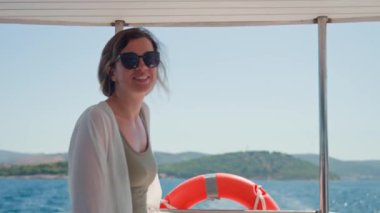 Güneş gözlüğü takan kadın, güneşli bir günde arka planda deniz olan tekne gezisinde esintiden hoşlanıyor. Yaz tatili konsepti.