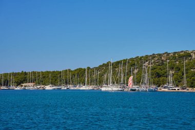 Güneşli bir günde açık mavi gökyüzünün altında limana yanaşmış lüks yatlar.