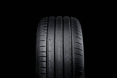 Siyah zemin üzerinde simetrik lastik olan yeni yaz araba lastiğinin ön görüntüsü