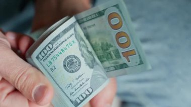 El ele tutuşup banknotları sayıyoruz. Amerikan dolarlarını elinde tutan adam. Para yönetimi, zenginlik veya mali işlemler kavramı