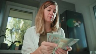 Evdeki banknotları sayan bir kadın. Amerikan dolarlarını elinde tutan kadın. Para yönetimi, zenginlik veya mali işlemler kavramı