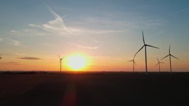 Gün batımında kırsal alanda siluetli rüzgar türbinleri. Rüzgar santrali temiz enerji üretiyor. Yenilenebilir ve sürdürülebilir enerji kavramı