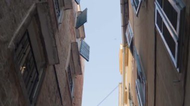 Dar sokakları, açık pencereleri ve açık gökyüzü olan binaları ayıran yukarı doğru manzara. Hırvatistan 'ın Split kentinde tarihi sokakta yürüyüş