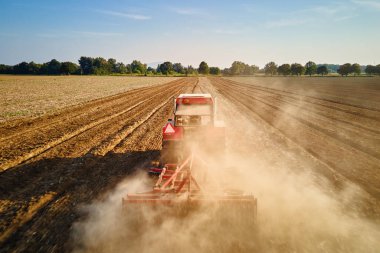 Kırmızı traktör tarlada çalışıyor, kuru toprak ekip biçiyor, hava manzarası var. Tarım sektörü konsepti. Küçük tarım kavramı