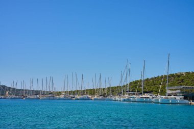 Güneşli bir günde açık mavi gökyüzünün altında limana yanaşmış lüks yatlar.