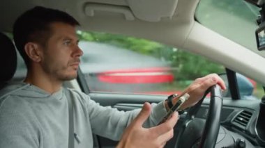 Sürücü araba kullanırken akıllı telefon kullanıyor, telefonundaki mesajlar dikkatini dağıtıyor. Tehlikeli araç kullanma, trafik kurallarının ihlali.