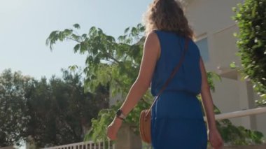 Hırvatistan 'ın kıyı kenti sokaklarında gezinen turistler, yaz tatilinde güneşli havanın keyfini çıkarıyorlar. Güneş gözlüğü takan ve mavi elbiseli güzel bir kadın dışarı çıkıyor.