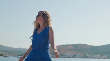 Yaz tatilinin tadını çıkaran kadın. Adriyatik Denizi seti boyunca rüzgar saçlarıyla yürüyen mutlu bir bayan turist. Sahil kasabasında arka planda deniz olan genç bir bayan gezgin.