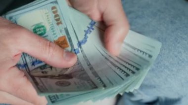 El ele tutuşup banknotları sayıyoruz. Amerikan dolarlarını elinde tutan adam. Para yönetimi, zenginlik veya mali işlemler kavramı