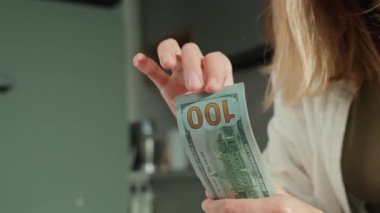 Evdeki banknotları sayan bir kadın. Amerikan dolarlarını elinde tutan kadın. Para yönetimi, zenginlik veya mali işlemler kavramı