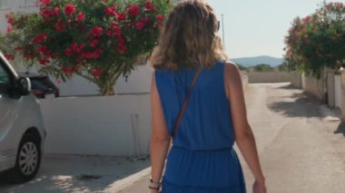 Hırvatistan 'ın kıyı kenti sokaklarında gezinen turistler, yaz tatilinde güneşli havanın keyfini çıkarıyorlar. Güneş gözlüğü takan ve mavi elbiseli güzel bir kadın dışarı çıkıyor.
