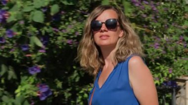 Hırvatistan 'ın kıyı kenti sokaklarında gezinen turistler, yaz tatilinde güneşli havanın keyfini çıkarıyorlar. Güneş gözlüğü takan ve mavi elbiseli güzel bir kadın dışarı çıkıyor.