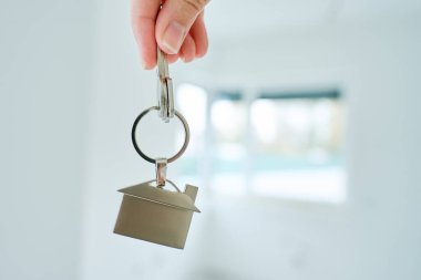 Yeni bulanık dairenin önündeki ev şeklindeki anahtarlıkla el ele tutuşun. İpotek ve yeni ev satın alma kavramı. Gayrimenkul işlemleri