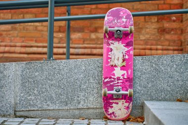 Şehir caddesinde taş duvara karşı çizilmiş pembe kaykay kullanılmış. Kentsel spor ve gençlik alt kültür kavramı