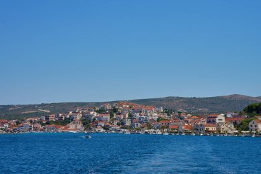 Yamaçta açık mavi sular boyunca yanaşmış tekneleri olan renkli kıyı evleri olan deniz kenarı kasabası. Hırvatistan 'ın Rogoznica kentindeki Adriyatik Denizi' nde yaz tatili için konut