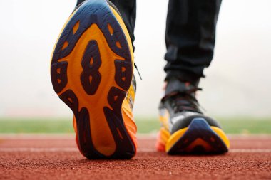 Stadyumda spor eğitimi alan tek kişilik koşu ayakkabılarının yakın çekimi. Spor ayakkabılı sporcu bacakları pist yüzeyinde