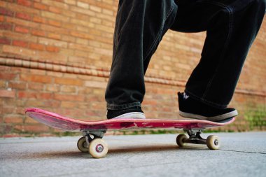 Şehir sokağında kaykaycı numaralar yapıyor. Kaykayla dengede duran bol kot giyen patencilere yaklaş. Gençlik alt kültürü kavramı