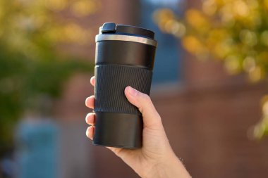 Bulanık sonbahar arka planında yeniden kullanılabilir kahve fincanı tutan kadın. Sürdürülebilir ve çevre dostu yaşam kavramı