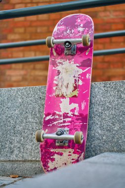 Şehir caddesinde taş duvara karşı çizilmiş pembe kaykay kullanılmış. Kentsel spor ve gençlik alt kültür kavramı