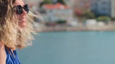 Yaz tatilinin tadını çıkaran kadın. Adriyatik Denizi seti boyunca rüzgar saçlarıyla yürüyen mutlu bir bayan turist. Sahil kasabasında arka planda deniz olan genç bir bayan gezgin.