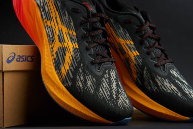 Modern Asics Novablast koşu ayakkabıları. Kutunun yanında siyah ve turuncu tasarım var. Arka planda bir çift spor ayakkabısı. Stüdyo çekimleri şık spor ayakkabılar. Wroclaw, Polonya - 6 Kasım 2024