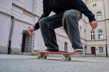 Şehir sokağında kaykaycı numaralar yapıyor. Kaykayla dengede duran bol kot giyen patencilere yaklaş. Gençlik alt kültürü kavramı