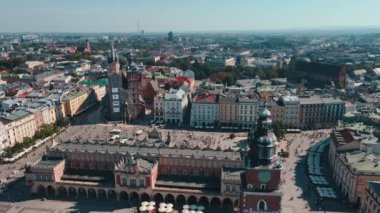Güneşli bir günde tarihi Kumaş Salonu Sukiennice 'in çevresindeki renkli binaların bulunduğu Krakow ana pazar meydanının hava manzarası. Polonya 'nın Krakow şehrinde turistler eski kentte yürüyor.