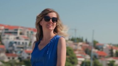 Yaz tatilinin tadını çıkaran kadın. Adriyatik Denizi seti boyunca rüzgar saçlarıyla yürüyen mutlu bir bayan turist. Sahil kasabasında arka planda deniz olan genç bir bayan gezgin.