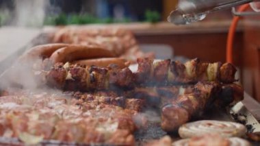 Sokak satıcısı Polonya, Wroclaw 'daki Noel pazarında ızgarada şiş ve sosis hazırlıyor. Sokak yemeklerini pişirme süreci