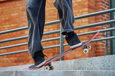 Kaykaycı şehir sokağında eski numaralarını yapıyor. Kaykayla dengede duran bol kot giyen patencilere yaklaş. Gençlik alt kültürü kavramı