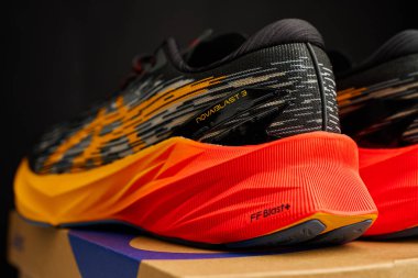 Modern Asics Novablast koşu ayakkabıları. Kutunun yanında siyah ve turuncu tasarım var. Arka planda bir çift spor ayakkabısı. Stüdyo çekimleri şık spor ayakkabılar. Wroclaw, Polonya - 6 Kasım 2024