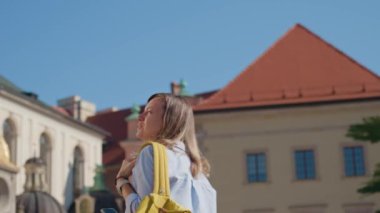 Polonya, Krakow 'da sarı sırt çantası taşıyan bir kadın yürüyor. Yaz günü Avrupa sokaklarını keşfeden kadın turist