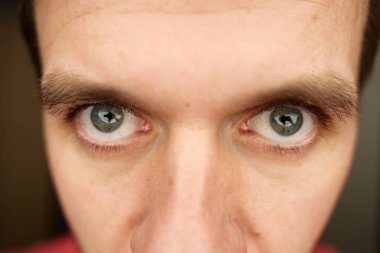 Gri gözlü, yoğun bakışlar. Odaklanmış ifadesi olan bir erkek yüzü. Kameraya yoğun bakan insan gözlerini kapat