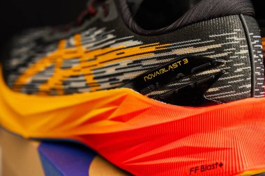 Modern Asics Novablast koşu ayakkabıları. Kutunun yanında siyah ve turuncu tasarım var. Arka planda bir çift spor ayakkabısı. Stüdyo çekimleri şık spor ayakkabılar. Wroclaw, Polonya - 6 Kasım 2024