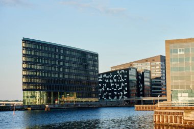 Danimarka 'nın Kopenhag limanı boyunca cam cepheli modern ofis binaları. Çağdaş İskandinav mimarisi. Şehir setinin panoramik manzarası. Kopenhag, Danimarka - 26 Haziran 2024