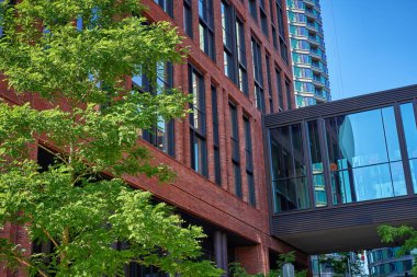 Modern kırmızı tuğla binanın yanındaki yemyeşil ağaç. Konut binası cephesi. Çağdaş mimari şehir tasarımı