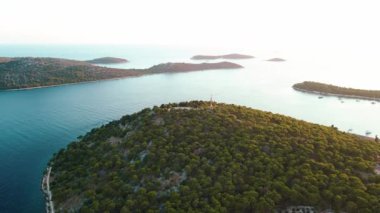 Hırvatistan 'ın Rogoznica kenti yakınlarındaki Adriyatik Denizi' ndeki yemyeşil bitki örtüsüyle kaplı adanın havadan görünüşü. Gün batımında deniz manzaralı kıyı şeridi