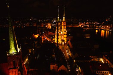 Wroclaw şehrinin hava manzarası gece aydınlandı. Gün batımında Ostrow Tumski 'deki St. John Katedrali. Wroclaw, Polonya Panoraması