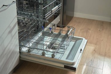 Boş rafları olan boş bulaşık makinesini aç ve modern mutfakta yüklemeye hazır bir sepet uzat. Ev aletleri