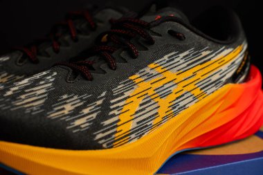 Modern Asics Novablast koşu ayakkabıları. Kutunun yanında siyah ve turuncu tasarım var. Arka planda bir çift spor ayakkabısı. Stüdyo çekimleri şık spor ayakkabılar. Wroclaw, Polonya - 6 Kasım 2024