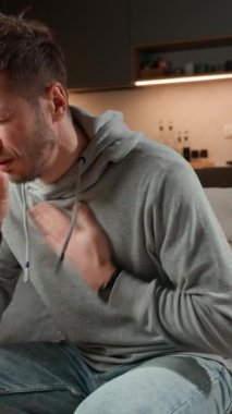 Evdeki kanepede oturan hasta bir adam, öksürüyor, göğüs ağrısı ve solunum sorunları, grip, astım ya da bronşit belirtileri gösteriyor. Hastalık, enfeksiyon ve hastalık konsepti