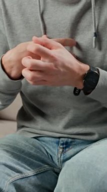 Kanepede otururken bileğini kaşıyan adamın yakın çekimi. Deri tahrişi ya da alerjik reaksiyon