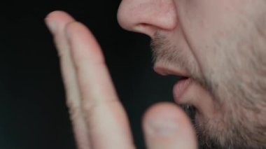 Ağızdan kötü bir nefes. Adamın nefesini kontrol ederken eline nefes verirken, ağız hijyeni ya da kötü kokan nefesle ilgili endişelerini gösterir.