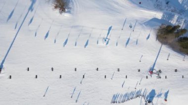 Kayakçılarla, snowboardcularla ve kayak pistlerindeki iskemlelerle kış tatil köyünün hava manzarası. Kış sporları ve açık hava aktiviteleri