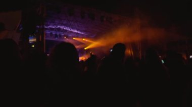 Canlı konser sahnesi, sahne ışıkları altında bando sahne alıyor. İnsanlar açık hava konserinde canlı müzik dinlemekten hoşlanıyorlar.