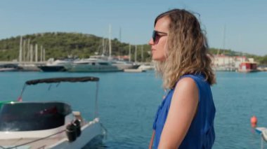 Yaz tatilinin tadını çıkaran kadın. Adriyatik Denizi seti boyunca rüzgar saçlarıyla yürüyen mutlu bir bayan turist. Sahil kasabasında arka planda deniz olan genç bir bayan gezgin.
