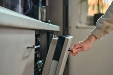 Modern mutfaktaki bulaşık makinesinin kadın eli kapısını kapatın. Kullanışlı bulaşık yıkama için tasarlanmış enerji tasarruflu ev aleti